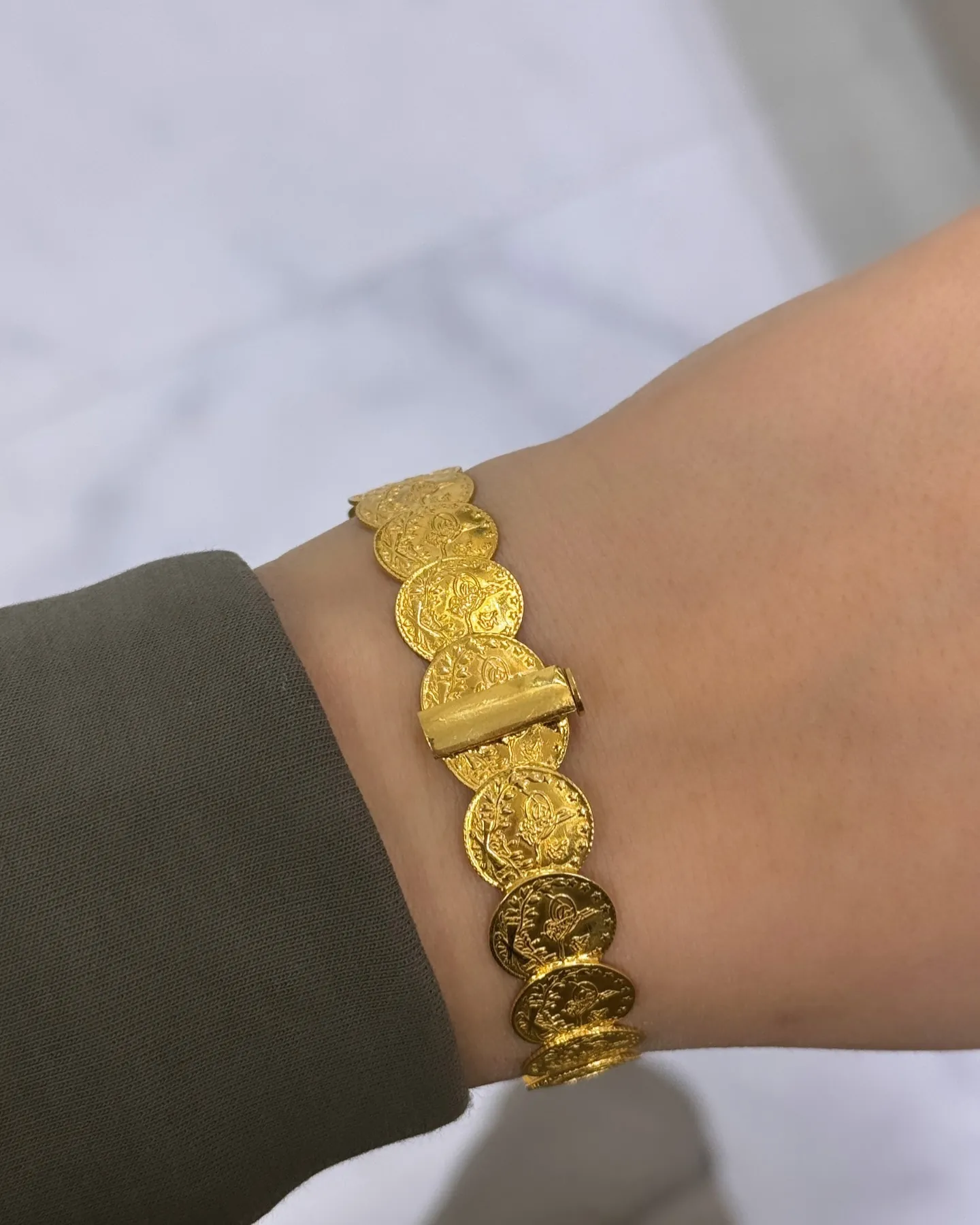 Armband aus aneinandergereihten Goldmünzen am Handgelenk